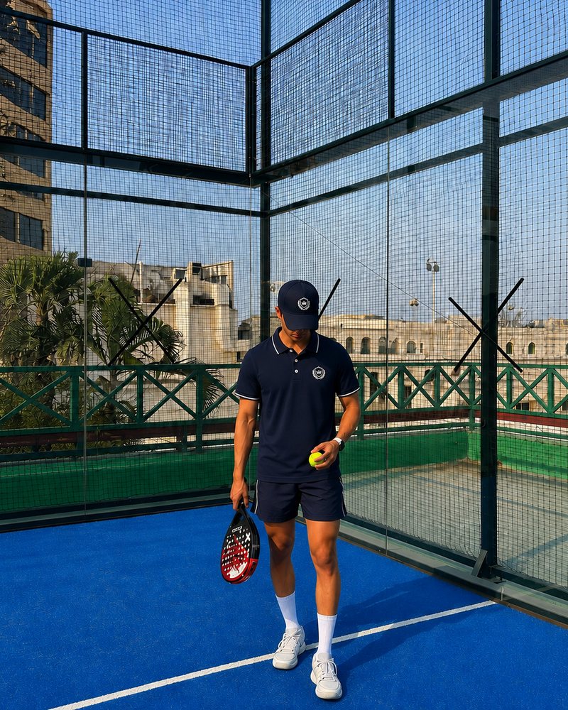 Model in the navy polo and shorts on a padel court